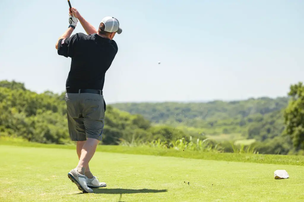 man in black shirt and brown shorts holding golf club during daytime