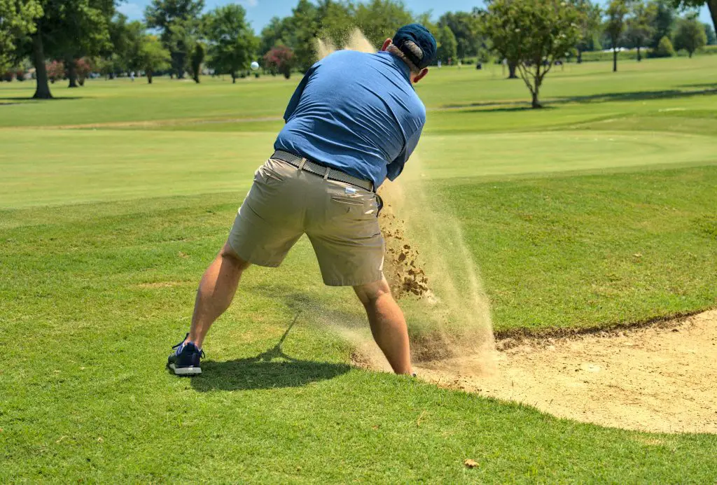 man in blue t-shirt and brown shorts playing golf during daytime