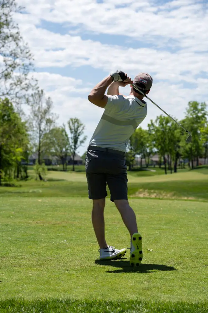 man in white t-shirt and black shorts holding golf club