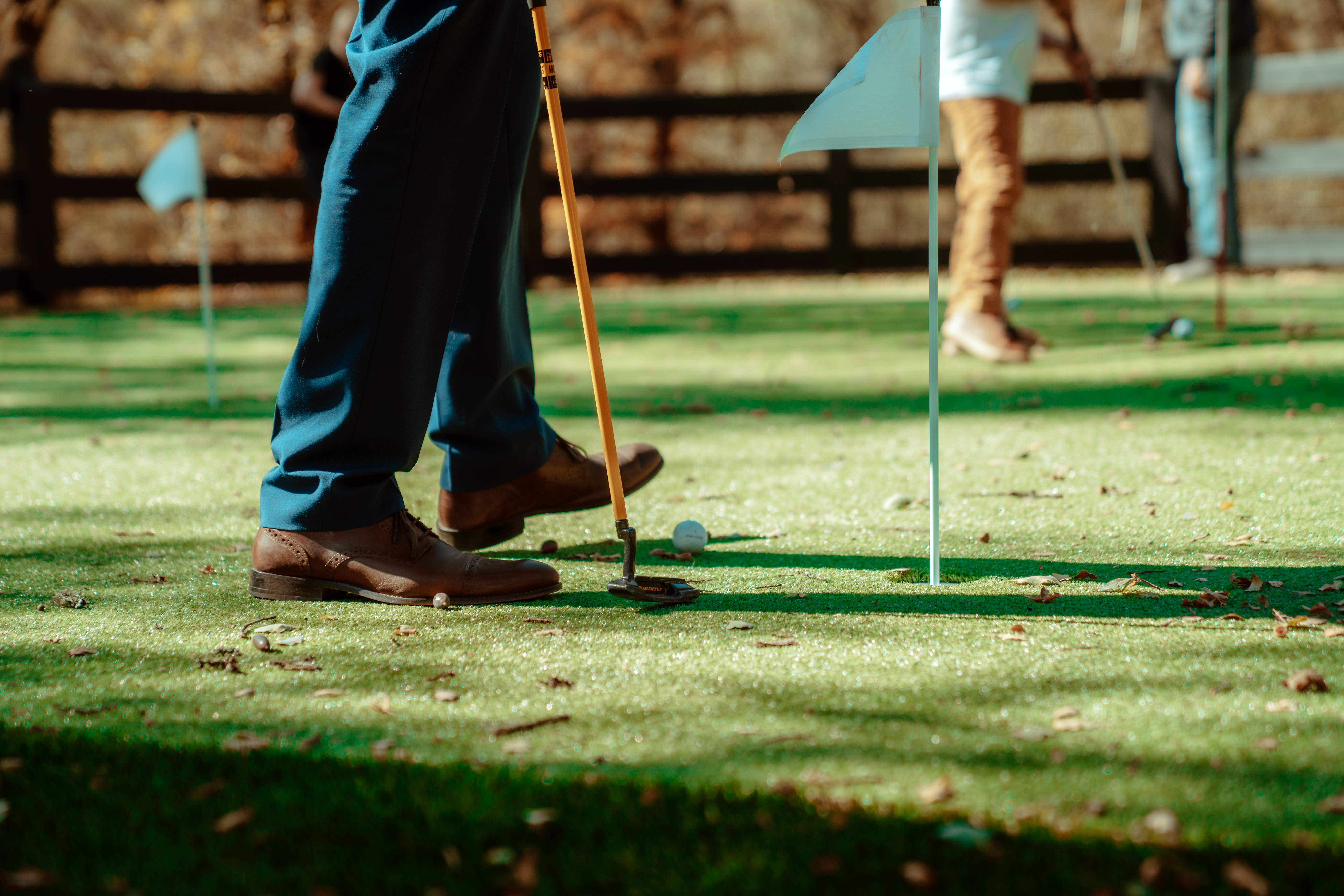 Putting on the green with a golf club and ball at a lawn party.